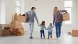 Family moving out of their home, holding hands and carrying boxes. 