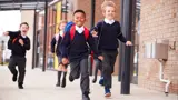 Children happily running in front of a school.