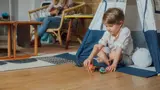 Young boy happily playing in a teepee.