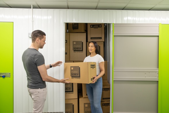 People holding Make Space boxes in a storage unit.